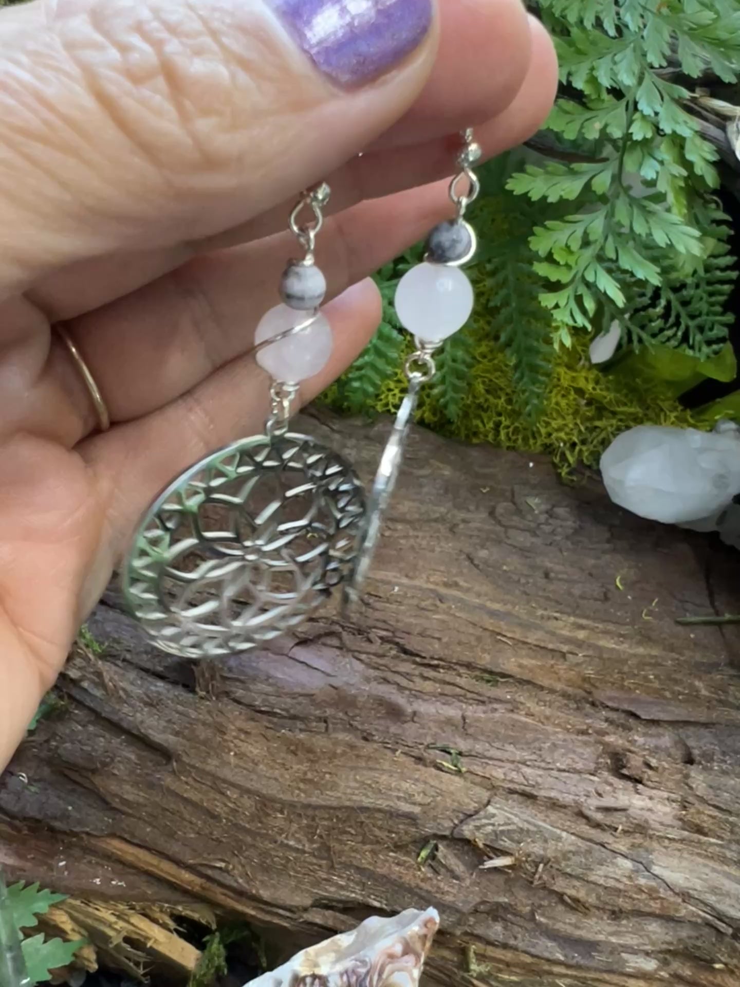 Emotional healing crystal earrings with pink beads and moon phases surrounded by moss