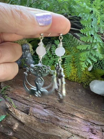 Spiritual rose quartz and clear quartz earrings surrounded by moss and natural textures

