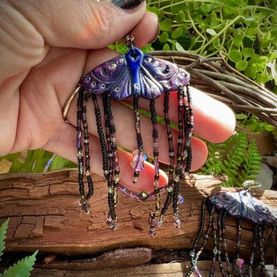 Close-up of iridescent beaded tassels shimmering in rainbow light on moth earrings
