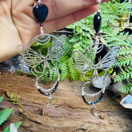 Magical transformation earrings with black agate and moon phases resting on rustic background