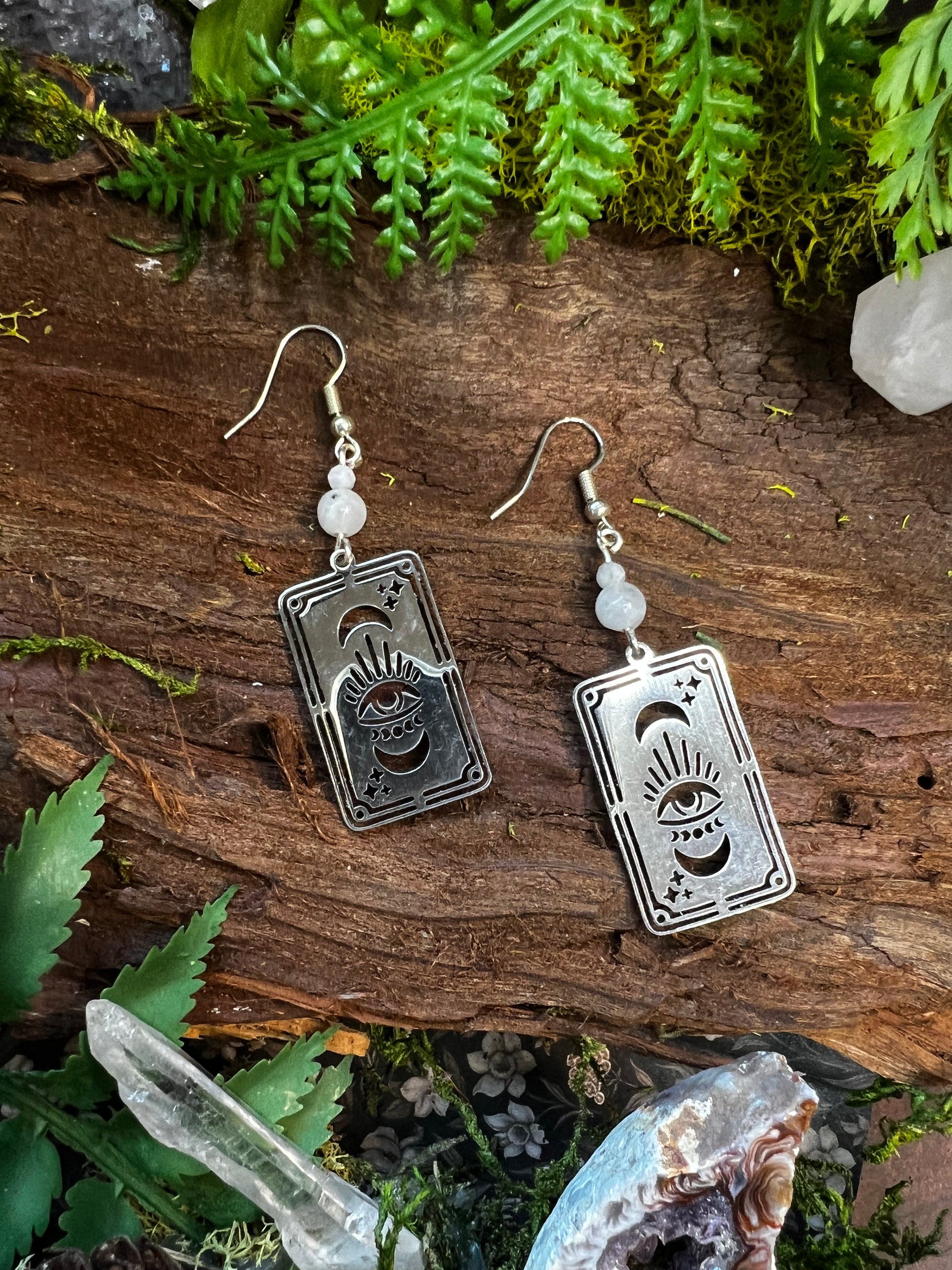 Spiritual tarot earrings with rainbow moonstone beads resting on rustic natural background