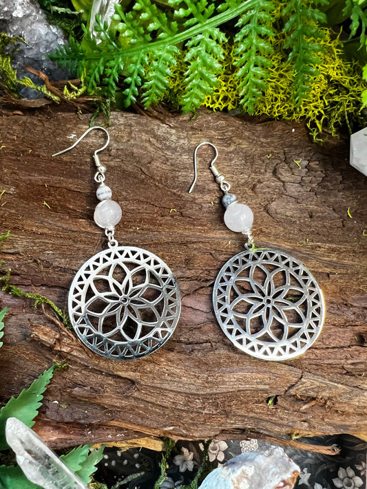 Silver mandala rose quartz and zebra jasper earrings on a wooden surface with greenery